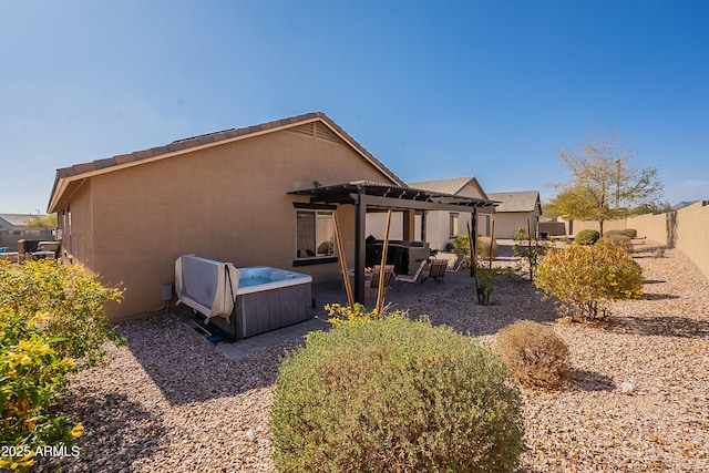 back of property with a fenced backyard, a pergola, a hot tub, stucco siding, and a patio area