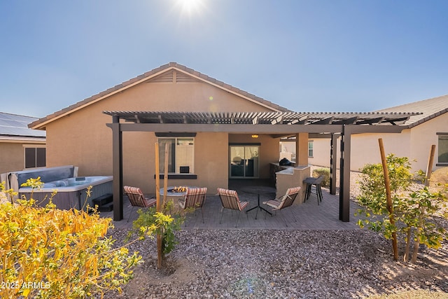 back of house featuring stucco siding, a pergola, a patio, a fire pit, and a hot tub