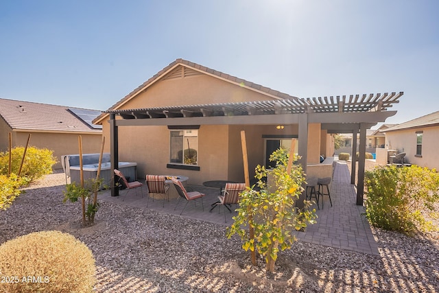 rear view of house featuring a hot tub, a pergola, and a patio