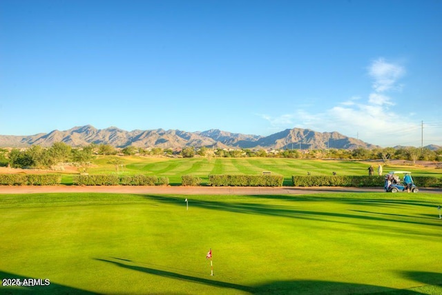 view of home's community with a mountain view, a lawn, and view of golf course