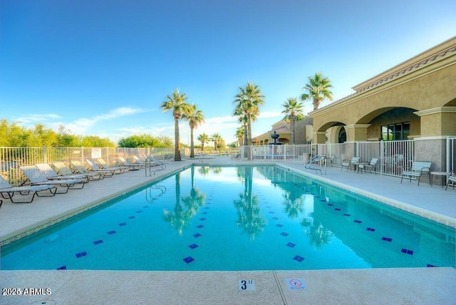 pool with a patio area and fence