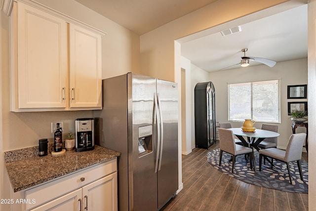 kitchen with dark stone countertops, dark wood-style floors, visible vents, stainless steel fridge with ice dispenser, and ceiling fan