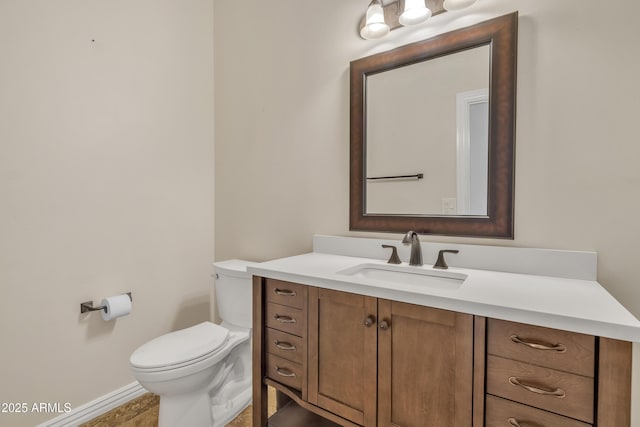 half bathroom with vanity, baseboards, and toilet