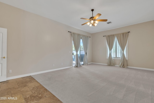 carpeted empty room featuring baseboards, a ceiling fan, and a wealth of natural light