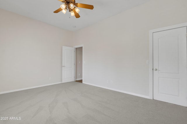 carpeted spare room featuring baseboards and ceiling fan