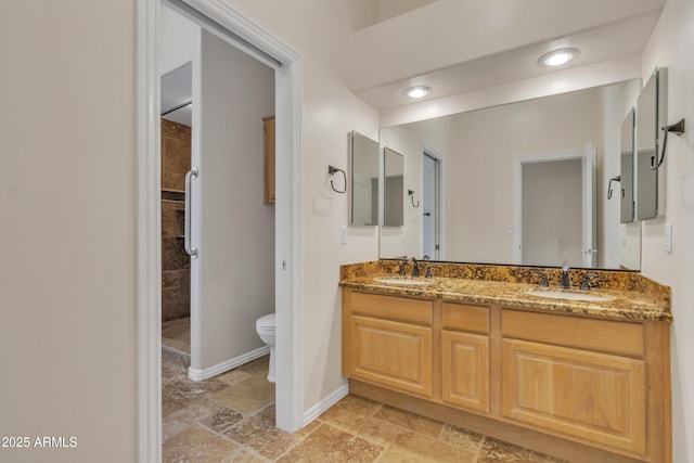 bathroom featuring stone tile flooring, a sink, baseboards, and toilet