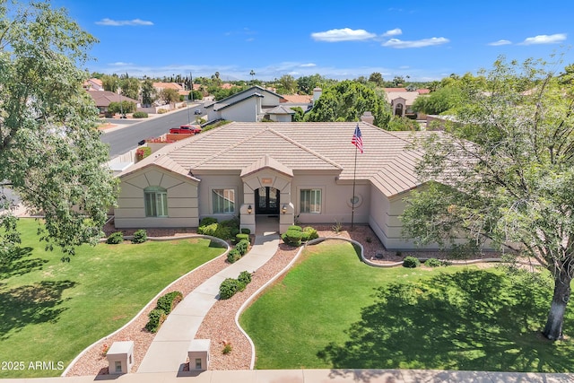 ranch-style home featuring a tiled roof, french doors, a front yard, and stucco siding