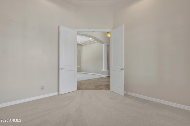carpeted empty room featuring arched walkways and baseboards