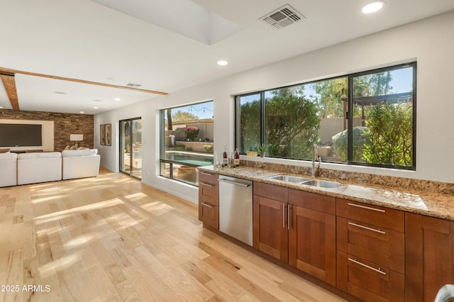 kitchen featuring dishwasher, light stone countertops, a wealth of natural light, sink, and light hardwood / wood-style flooring