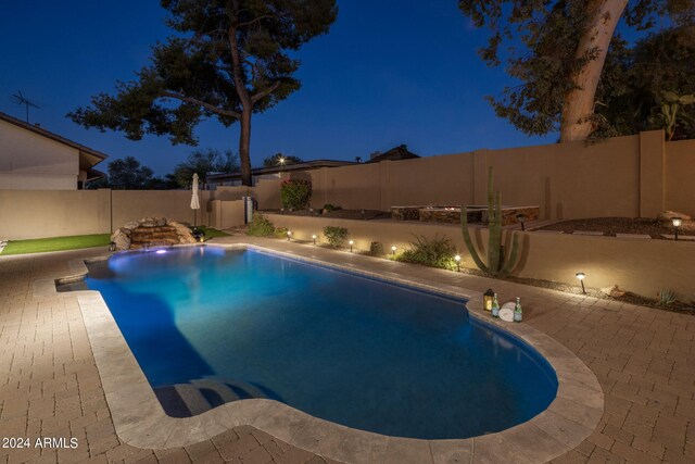 view of pool at twilight