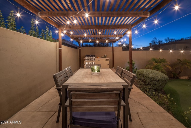 patio at night with a pergola and an outdoor kitchen