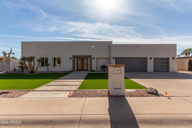 pueblo revival-style home with a front lawn, a garage, and french doors