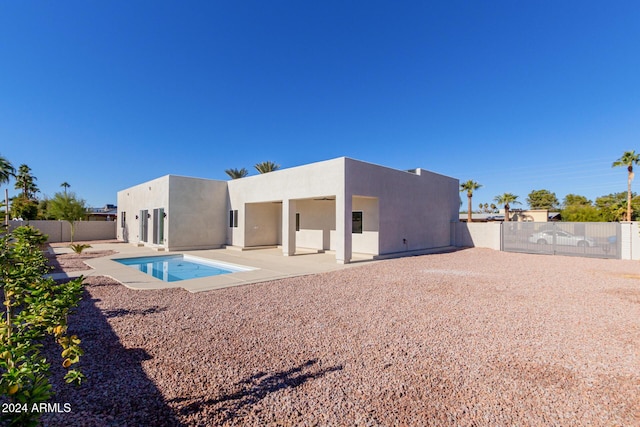 rear view of property with a fenced in pool and a patio area