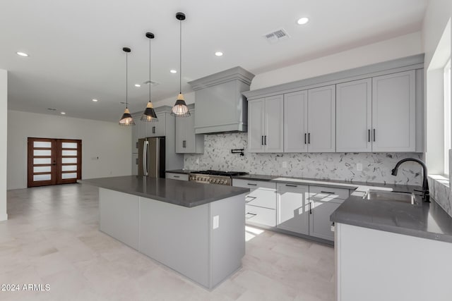 kitchen with pendant lighting, sink, appliances with stainless steel finishes, a kitchen island, and custom range hood