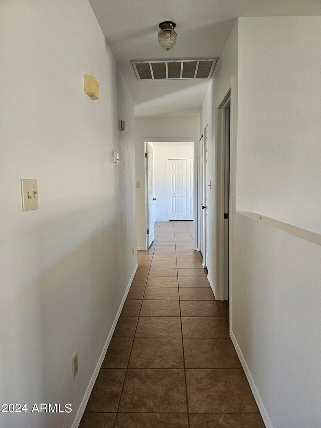hall with dark tile flooring