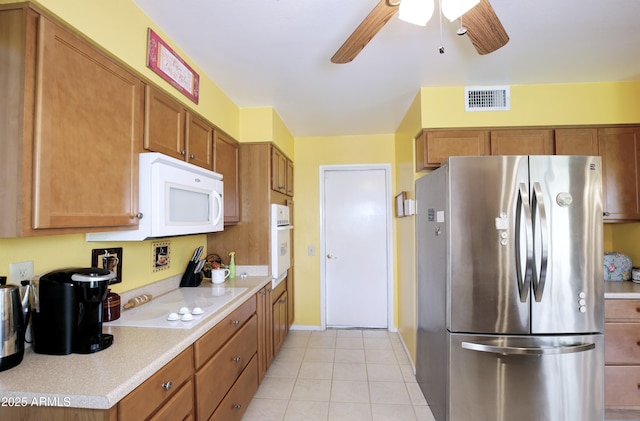 kitchen with light countertops, white appliances, brown cabinetry, and visible vents