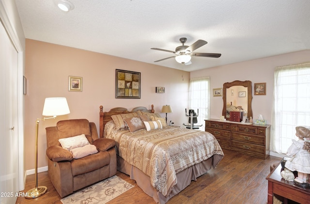 bedroom featuring multiple windows, dark wood finished floors, a textured ceiling, and ceiling fan