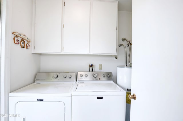 clothes washing area with cabinet space, water heater, and washing machine and clothes dryer