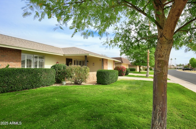 exterior space featuring an attached garage, driveway, a front lawn, and brick siding