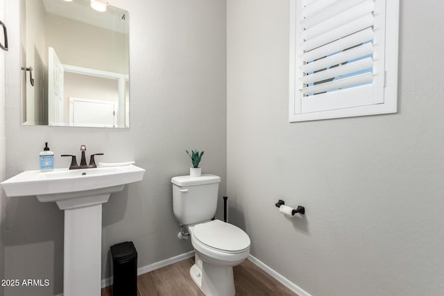 half bath featuring toilet, wood finished floors, and baseboards