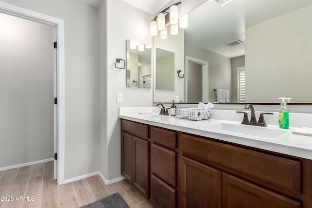 bathroom with double vanity, visible vents, a sink, and wood finish floors