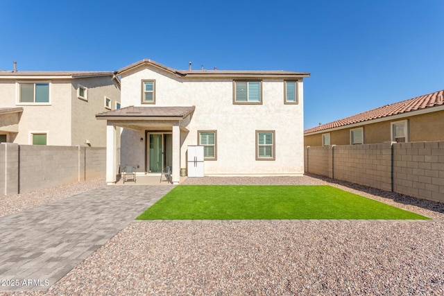 rear view of house with a fenced backyard, a patio, a lawn, and stucco siding