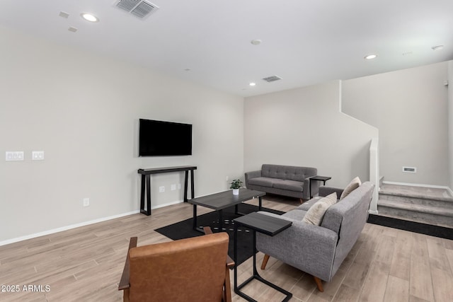 living area featuring visible vents, baseboards, light wood-style floors, and stairs