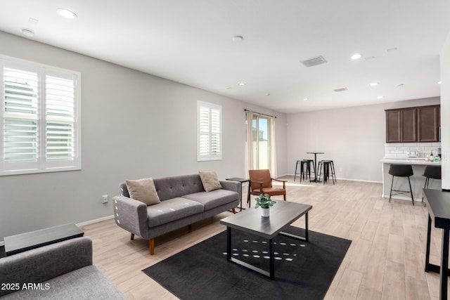 living area with visible vents, baseboards, light wood finished floors, and recessed lighting
