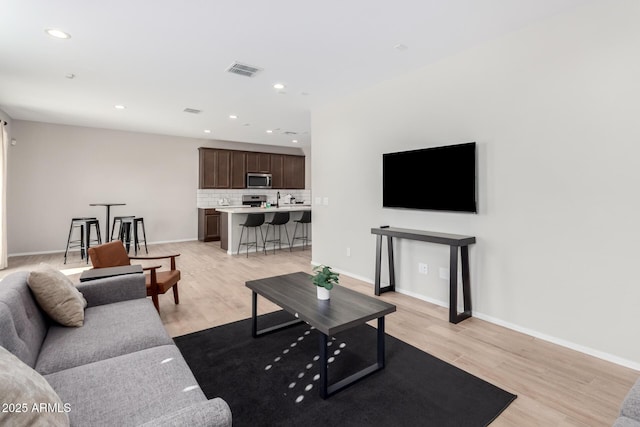 living area featuring visible vents, light wood-type flooring, and baseboards