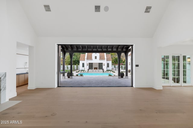 spare room with light wood-type flooring and high vaulted ceiling