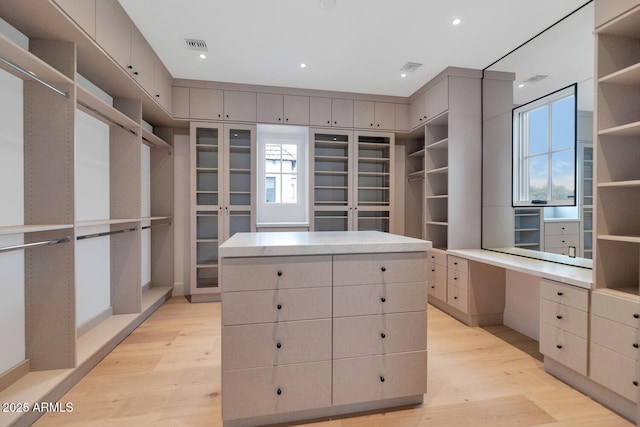 walk in closet with light hardwood / wood-style floors and built in desk