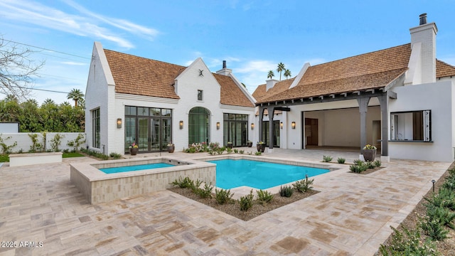 rear view of property featuring a patio and a swimming pool with hot tub