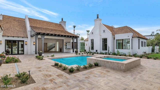 back of house with a patio area and a pool with hot tub