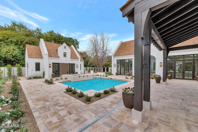 view of pool with a patio, french doors, an in ground hot tub, and an outdoor structure