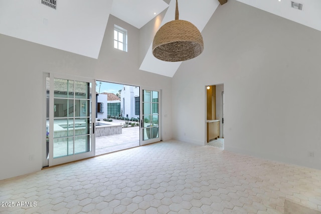 unfurnished living room with beamed ceiling, a healthy amount of sunlight, and a high ceiling