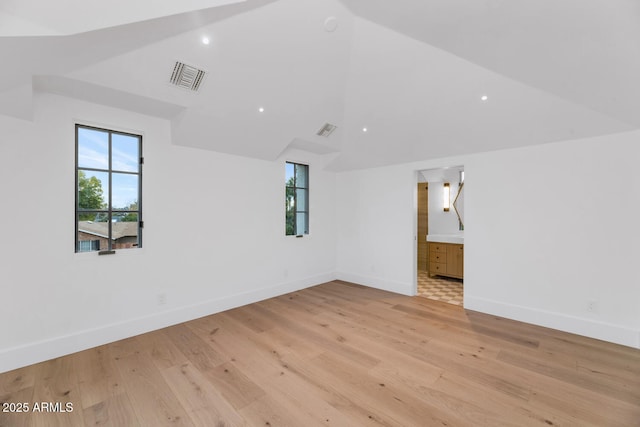 empty room with light wood-type flooring, high vaulted ceiling, and a wealth of natural light