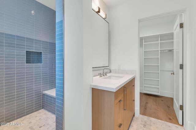 bathroom with tile patterned flooring, vanity, and tiled shower