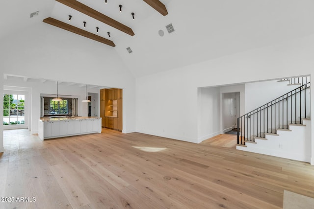 unfurnished living room with beamed ceiling, light hardwood / wood-style floors, and high vaulted ceiling