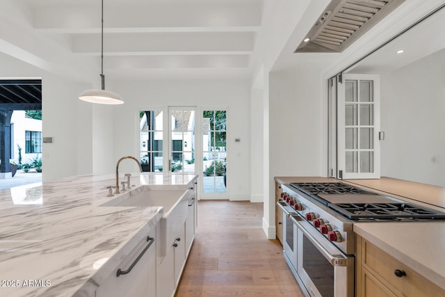 kitchen with white cabinetry, double oven range, light hardwood / wood-style floors, sink, and pendant lighting