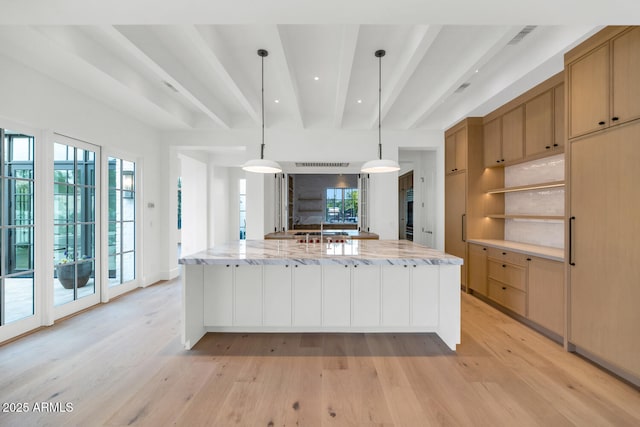 kitchen featuring a large island, light hardwood / wood-style flooring, light stone counters, beamed ceiling, and pendant lighting