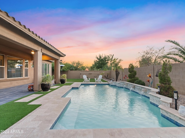 pool at dusk featuring a patio and pool water feature