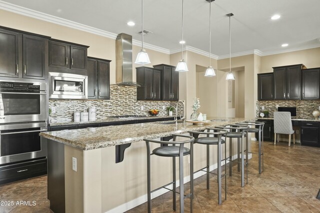 kitchen with light stone countertops, decorative light fixtures, sink, and a kitchen island with sink