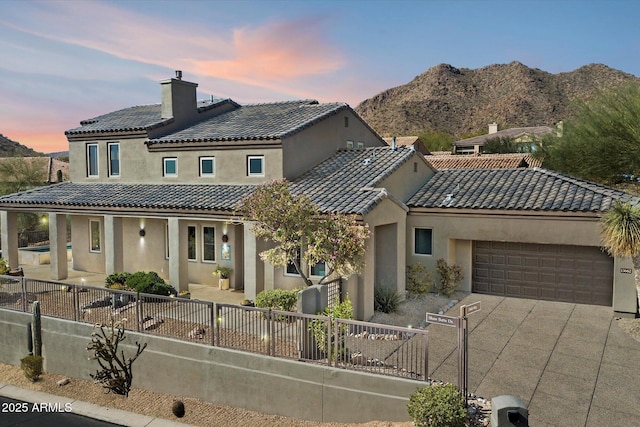 view of front of property featuring a fenced front yard, concrete driveway, a chimney, and a garage