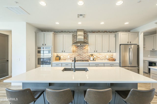 kitchen featuring a large island, wall chimney range hood, tasteful backsplash, wine cooler, and appliances with stainless steel finishes