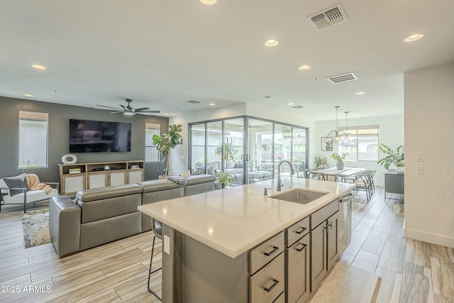 kitchen featuring pendant lighting, ceiling fan, sink, and an island with sink