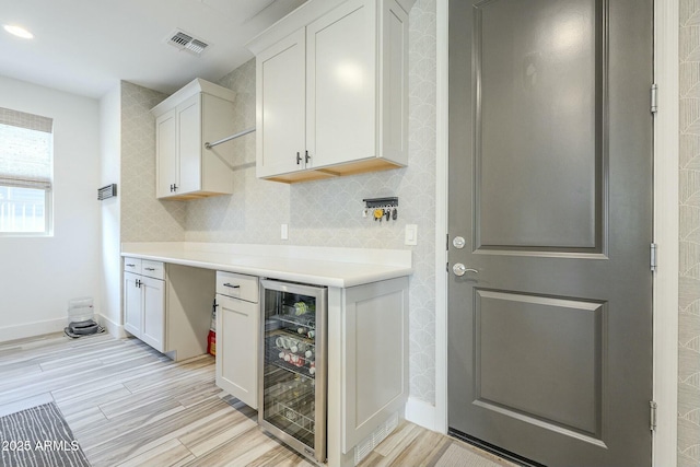 kitchen with light hardwood / wood-style flooring, white cabinetry, and beverage cooler