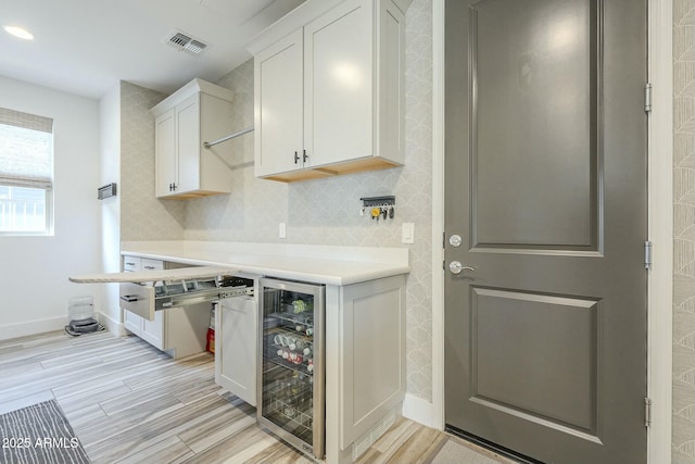 kitchen with wine cooler, light hardwood / wood-style floors, and white cabinetry