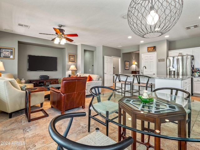 living room featuring ceiling fan with notable chandelier and sink