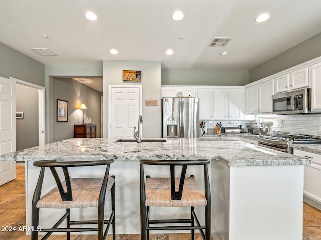 kitchen featuring stainless steel appliances, white cabinetry, sink, a kitchen breakfast bar, and a kitchen island with sink