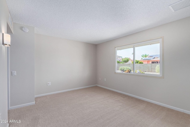 unfurnished room featuring light colored carpet and a textured ceiling